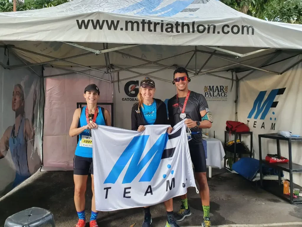 Três atletas segurando a bandeira da MFTeam