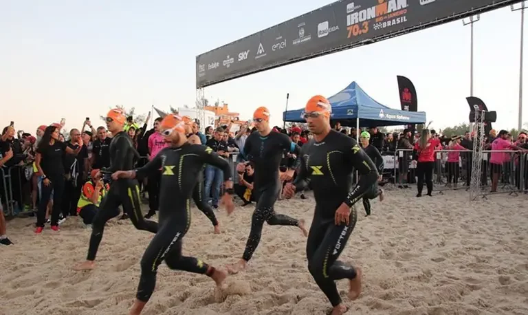 Atletas correndo em direção ao mar no Ironman 70.3 Rio de Janeiro 2022